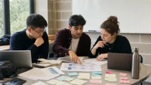 Realistic editorial photograph of international university students analysing a business case with notes and charts around a table